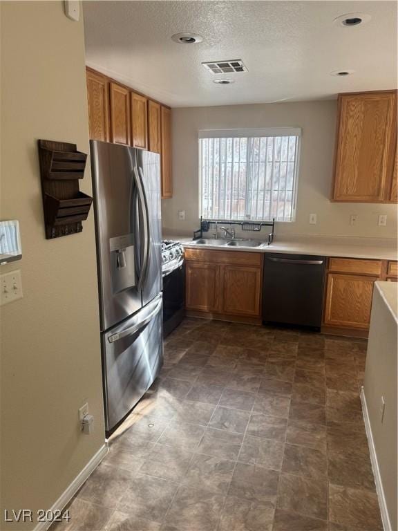 kitchen with sink, a textured ceiling, and stainless steel appliances