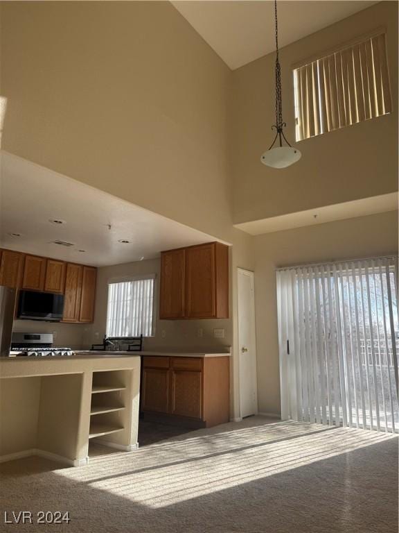 kitchen featuring a high ceiling, light carpet, range, and decorative light fixtures