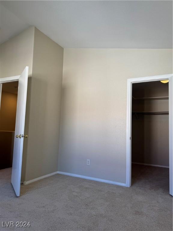 unfurnished bedroom with light carpet, a closet, and a walk in closet