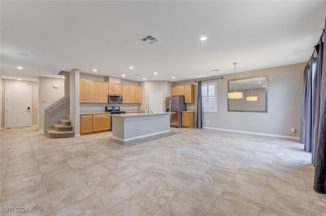 kitchen with light stone countertops, sink, decorative light fixtures, a kitchen island with sink, and appliances with stainless steel finishes