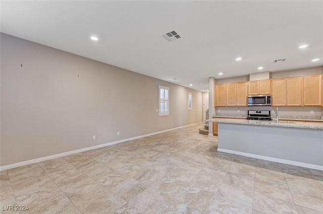 kitchen featuring appliances with stainless steel finishes, light stone counters, and light brown cabinetry