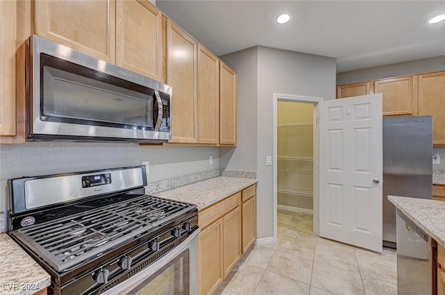 kitchen with light brown cabinets, light tile patterned floors, and stainless steel appliances