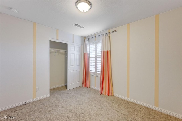 unfurnished bedroom with light colored carpet, a textured ceiling, and a closet