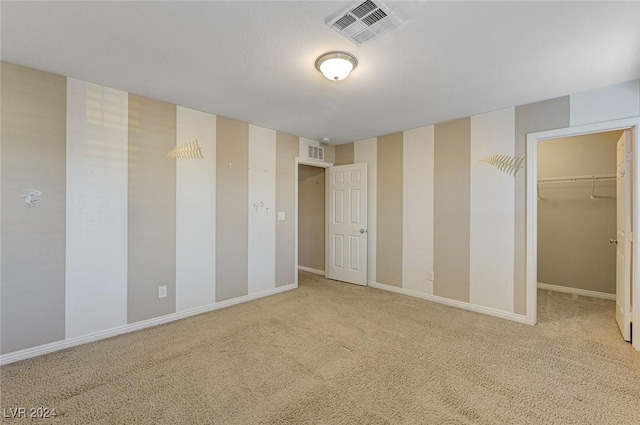 unfurnished bedroom featuring carpet flooring, a spacious closet, and a closet