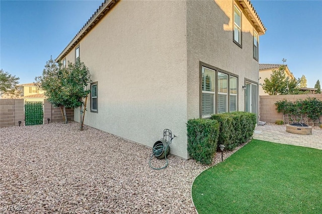 view of side of home with a lawn, a patio area, and a fire pit