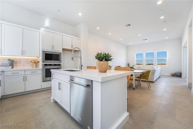 kitchen with white cabinetry, sink, a kitchen island with sink, decorative backsplash, and appliances with stainless steel finishes