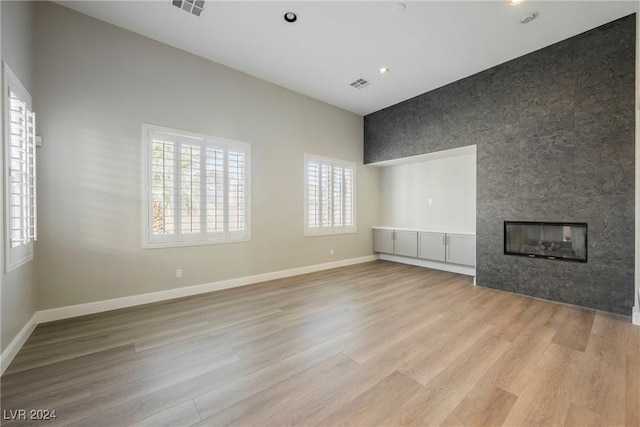 unfurnished living room with a multi sided fireplace and light wood-type flooring