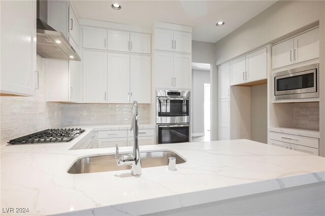 kitchen with white cabinetry, sink, stainless steel appliances, extractor fan, and decorative backsplash