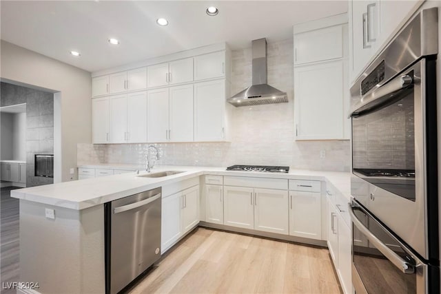 kitchen with white cabinets, wall chimney exhaust hood, and appliances with stainless steel finishes