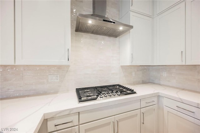 kitchen featuring white cabinets, tasteful backsplash, and wall chimney exhaust hood