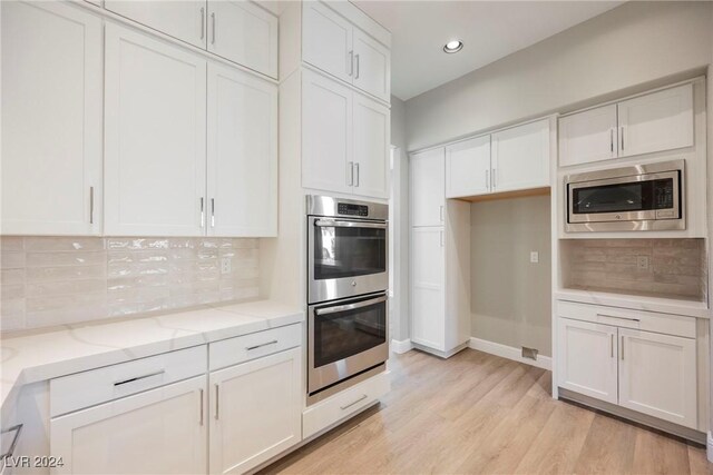 kitchen featuring backsplash, white cabinets, and stainless steel appliances