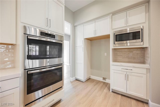 kitchen with decorative backsplash, stainless steel appliances, and white cabinetry