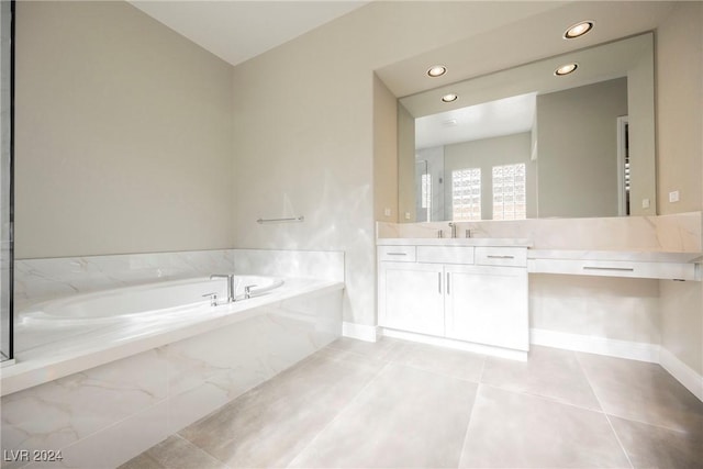 bathroom with tiled tub, tile patterned flooring, and vanity