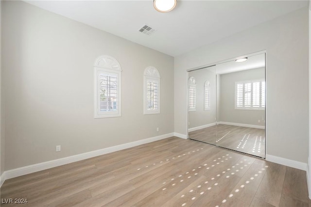 unfurnished bedroom featuring light hardwood / wood-style floors and a closet