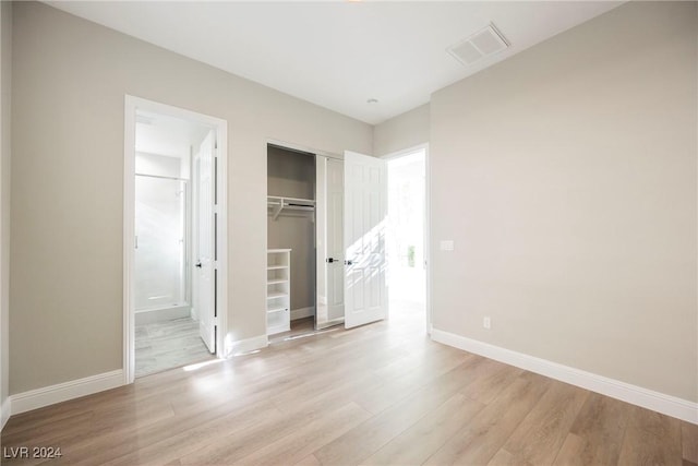 unfurnished bedroom featuring a closet, light hardwood / wood-style flooring, and ensuite bathroom