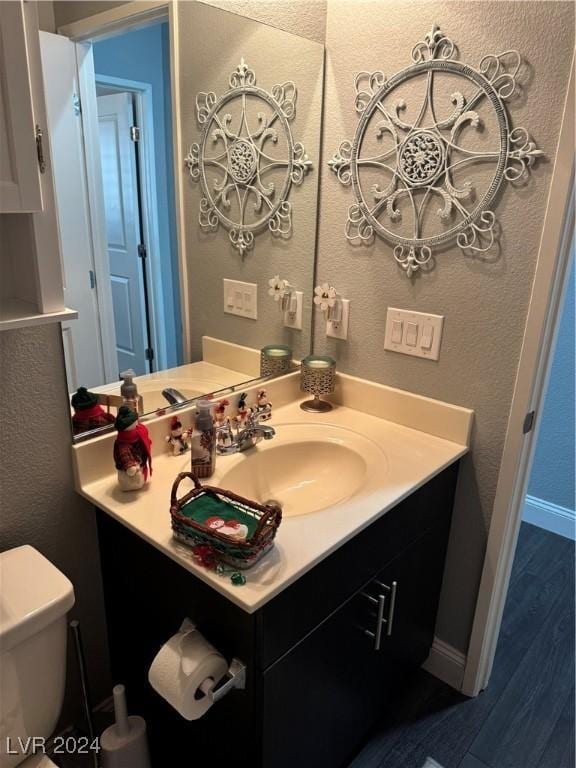 bathroom featuring hardwood / wood-style flooring, toilet, and vanity