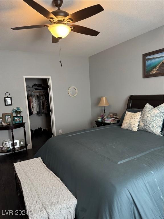 bedroom with a spacious closet, ceiling fan, a closet, and dark wood-type flooring