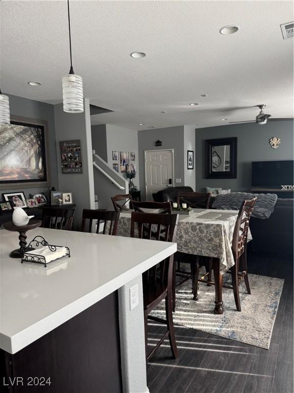 kitchen featuring a kitchen breakfast bar, ceiling fan, a textured ceiling, and decorative light fixtures