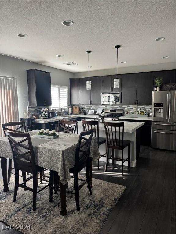 dining space with sink, a textured ceiling, and dark hardwood / wood-style floors