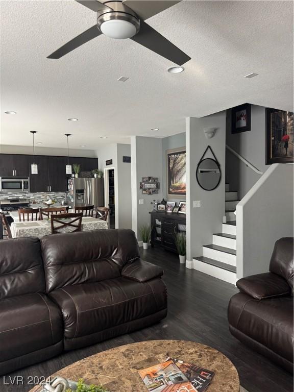 living room with ceiling fan, dark hardwood / wood-style flooring, and a textured ceiling