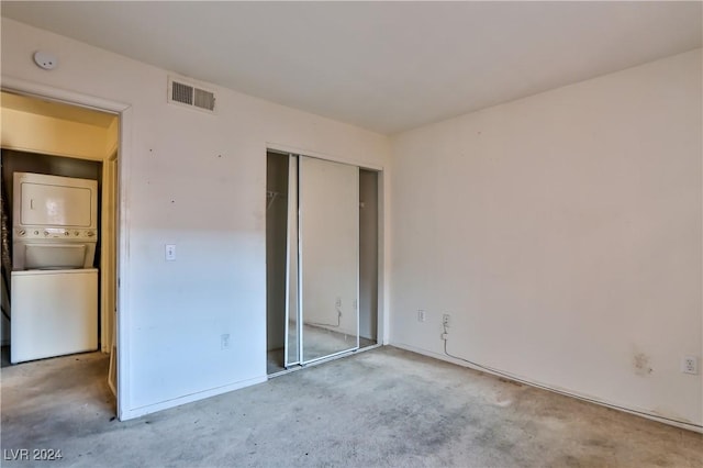 unfurnished bedroom featuring a closet and stacked washer and clothes dryer