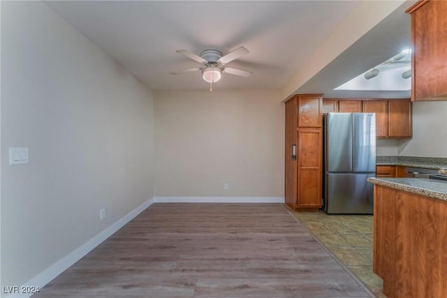 kitchen with light hardwood / wood-style floors, stainless steel refrigerator, and ceiling fan