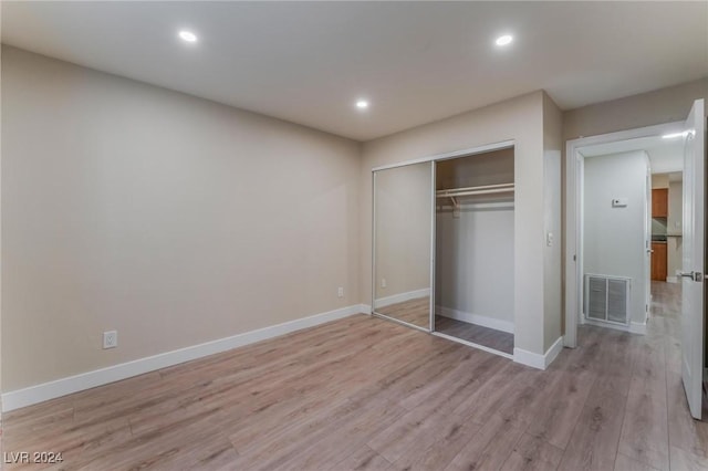 unfurnished bedroom with light wood-type flooring and a closet