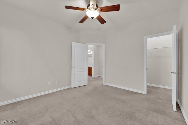 unfurnished bedroom featuring ceiling fan, a closet, a spacious closet, and light carpet