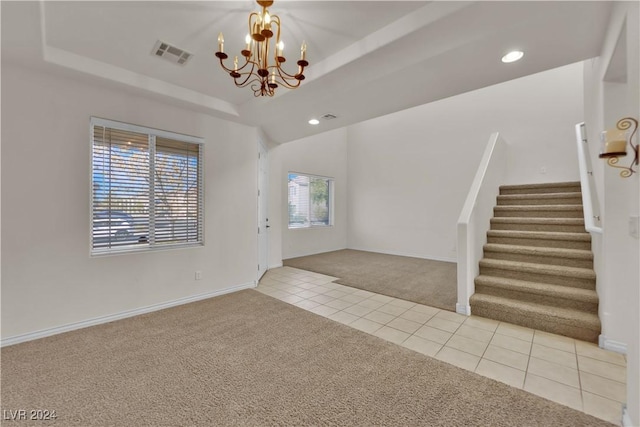 entrance foyer featuring light colored carpet, an inviting chandelier, and a tray ceiling