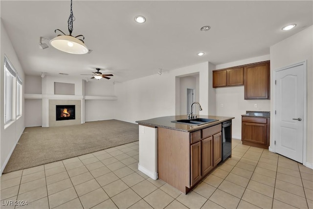 kitchen with dishwasher, an island with sink, sink, ceiling fan, and light carpet