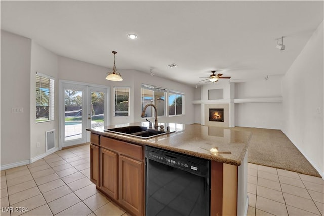 kitchen featuring light stone counters, black dishwasher, sink, and light tile patterned floors