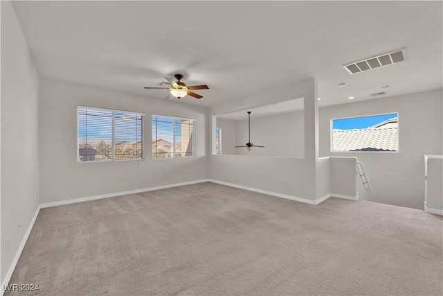 empty room with light carpet, ceiling fan, and a healthy amount of sunlight