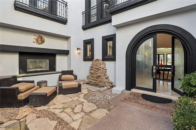 entrance to property with an outdoor hangout area, a balcony, and a patio area