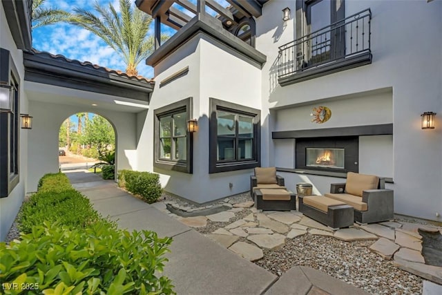 view of patio / terrace with a glass covered fireplace and a balcony