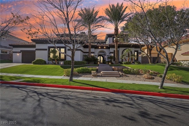 view of front facade featuring stucco siding, a yard, an attached garage, and a tiled roof