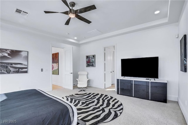 bedroom with a raised ceiling, ceiling fan, and light carpet