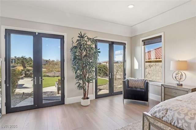 bedroom with access to exterior, french doors, and light hardwood / wood-style floors