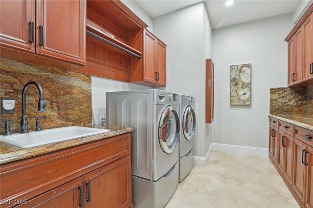 clothes washing area featuring cabinets, washing machine and dryer, and sink