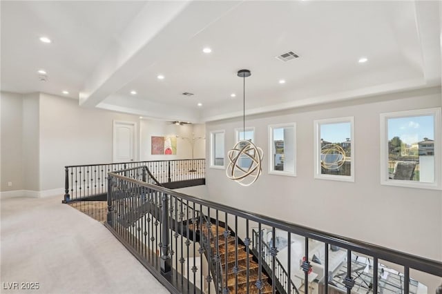 hall with a tray ceiling and light colored carpet