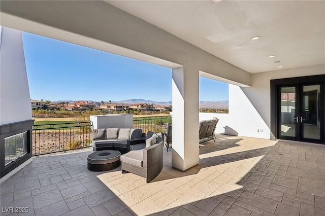 view of patio / terrace with a mountain view, an outdoor living space with a fire pit, and french doors