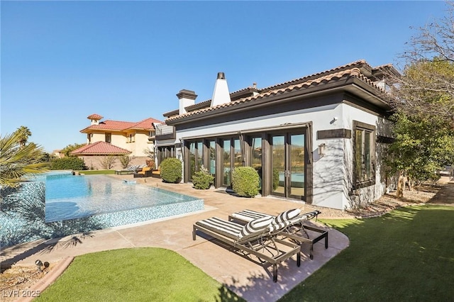 rear view of house featuring a tile roof, stucco siding, a chimney, an infinity pool, and a patio