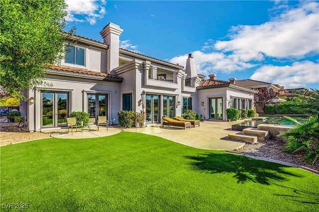 rear view of house featuring a patio area, a balcony, french doors, and a lawn