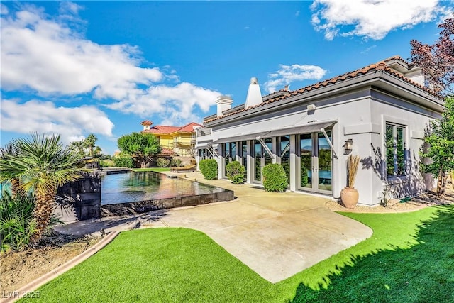 rear view of house featuring french doors, a lawn, a chimney, and stucco siding