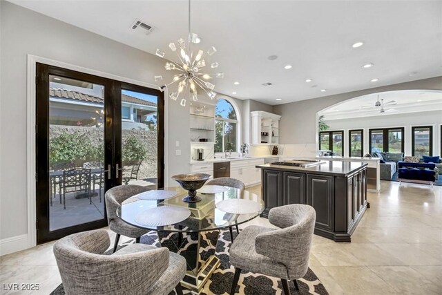 dining area with ceiling fan with notable chandelier and sink