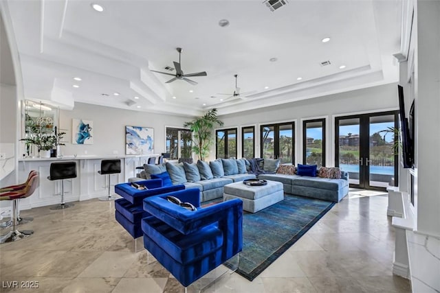 living room featuring a tray ceiling, ceiling fan, french doors, and plenty of natural light