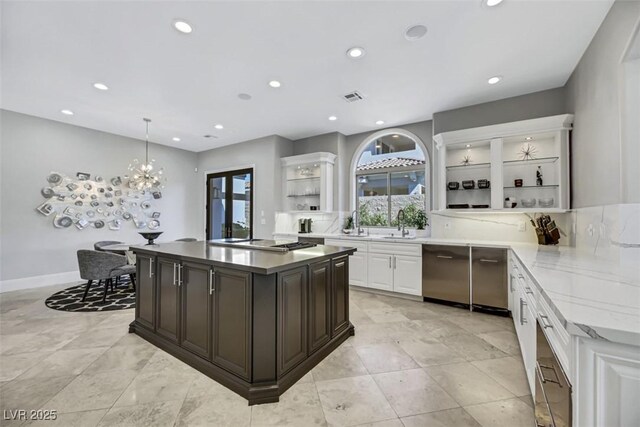 kitchen with hanging light fixtures, light stone countertops, dark brown cabinets, white cabinetry, and stainless steel appliances