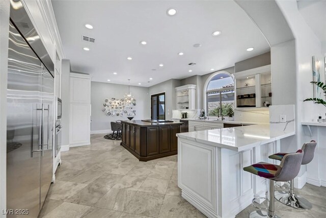 kitchen featuring kitchen peninsula, white cabinetry, pendant lighting, and stainless steel appliances