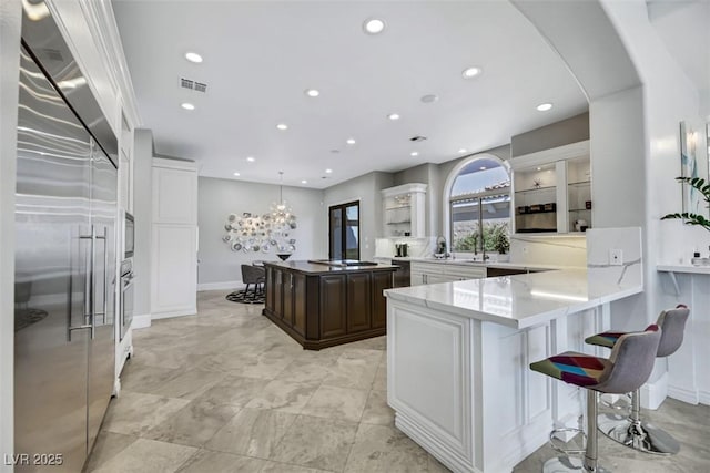 kitchen featuring visible vents, a kitchen breakfast bar, recessed lighting, appliances with stainless steel finishes, and dark brown cabinets