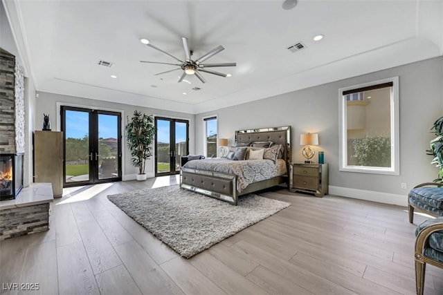 bedroom featuring visible vents, access to outside, wood finished floors, french doors, and a fireplace