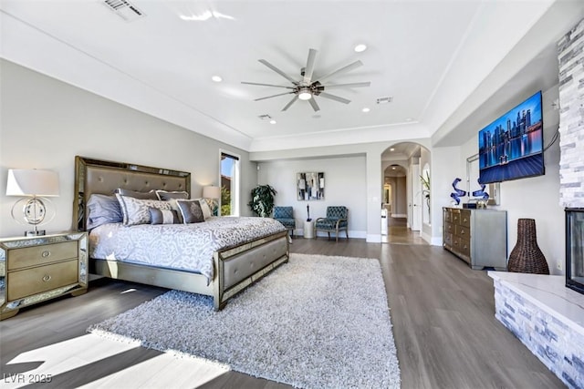 bedroom featuring visible vents, wood finished floors, recessed lighting, arched walkways, and baseboards